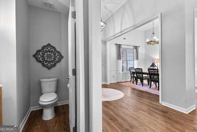 bathroom with baseboards, visible vents, toilet, wood finished floors, and a chandelier