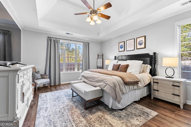 bedroom with multiple windows, visible vents, a raised ceiling, and dark wood-style flooring