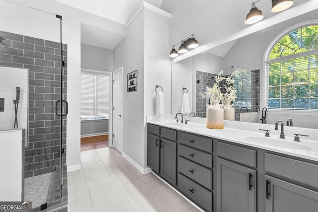 full bathroom with double vanity, a stall shower, tile patterned flooring, and a sink