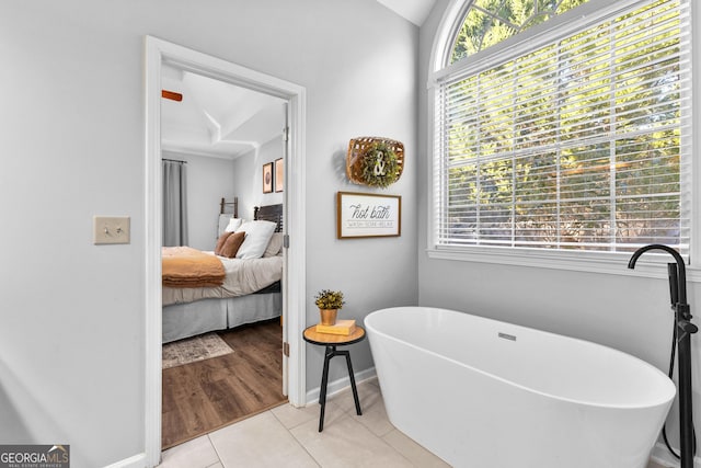 full bath featuring a freestanding tub, baseboards, ensuite bathroom, and tile patterned floors