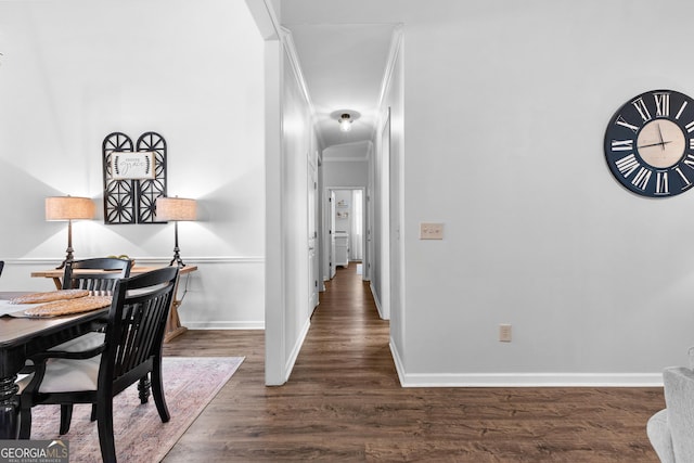 hallway with baseboards, ornamental molding, and dark wood-type flooring