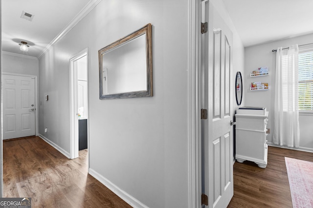 hall featuring ornamental molding, wood finished floors, visible vents, and baseboards