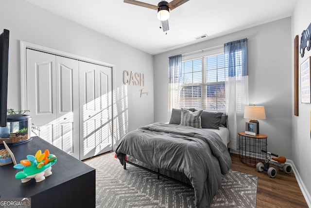 bedroom featuring baseboards, visible vents, a ceiling fan, wood finished floors, and a closet