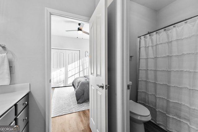 bathroom featuring connected bathroom, toilet, ceiling fan, wood finished floors, and vanity