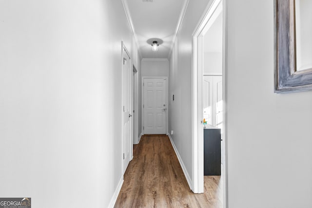 hallway featuring baseboards, wood finished floors, and crown molding