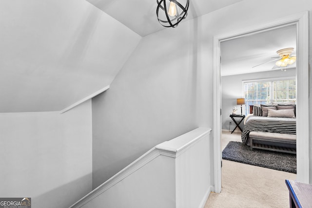 hallway with vaulted ceiling, carpet flooring, and an upstairs landing