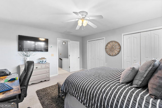 bedroom with ceiling fan, baseboards, two closets, and light colored carpet