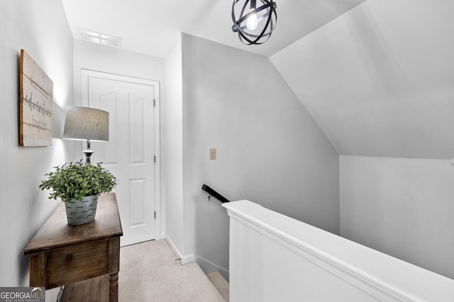 corridor featuring light carpet, baseboards, visible vents, vaulted ceiling, and an upstairs landing