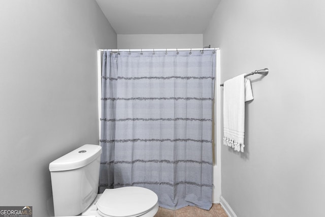 bathroom featuring a shower with curtain, toilet, and tile patterned floors