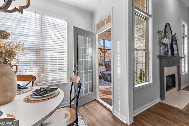 dining room with a fireplace with flush hearth, baseboards, crown molding, and wood finished floors