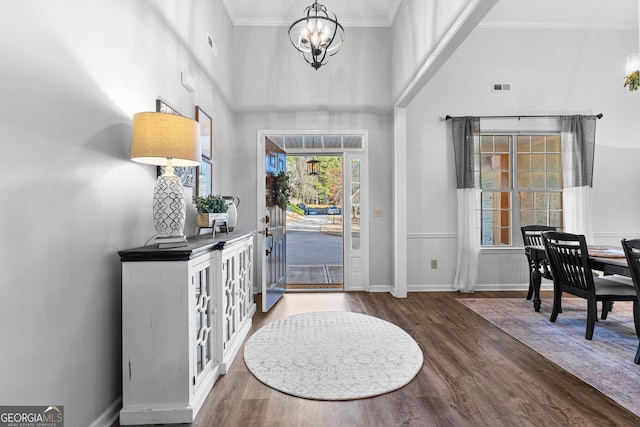 foyer with crown molding, visible vents, a notable chandelier, and wood finished floors