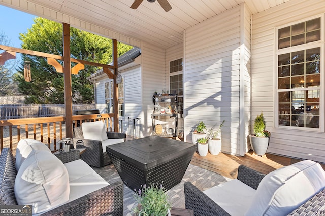 wooden terrace with ceiling fan, fence, and an outdoor living space