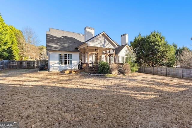 back of property with a chimney and a fenced backyard