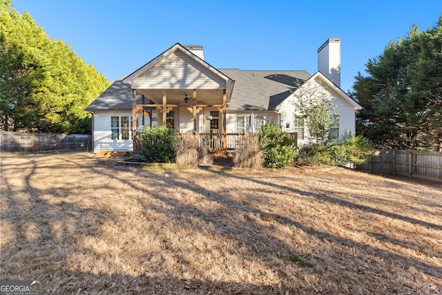 view of front of home featuring a chimney, fence, and a ceiling fan