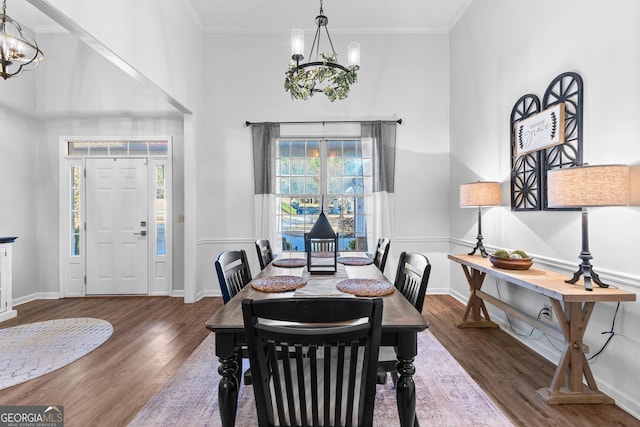 dining room with wood finished floors, crown molding, and an inviting chandelier