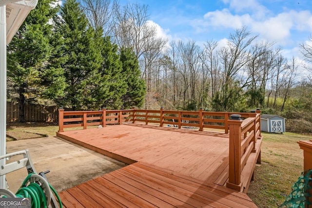 wooden deck with a shed, fence, a patio, and an outbuilding