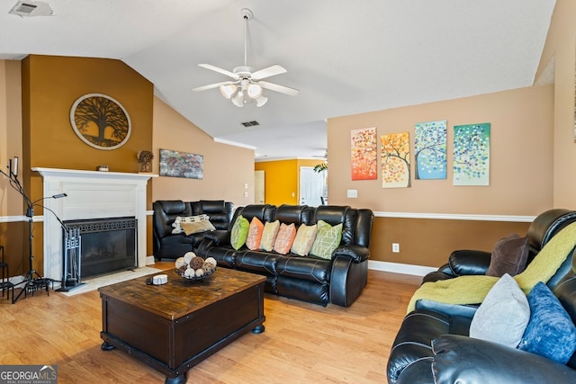 living room featuring lofted ceiling, light wood-type flooring, a fireplace with flush hearth, and visible vents