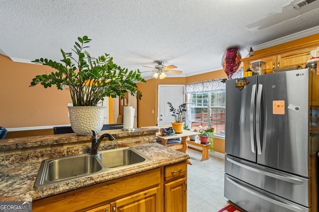 kitchen with freestanding refrigerator, brown cabinets, a sink, and visible vents