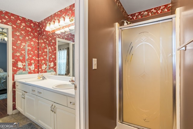 ensuite bathroom featuring wallpapered walls, a shower stall, and a sink