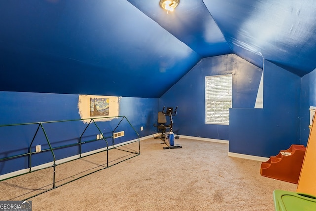 interior space with carpet floors, visible vents, vaulted ceiling, and baseboards