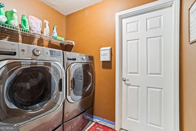 washroom featuring washer and dryer, laundry area, and a textured ceiling