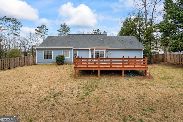 rear view of property with a deck, a lawn, and a fenced backyard