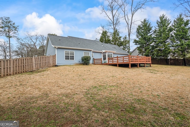 rear view of house with a fenced backyard, a yard, and a wooden deck