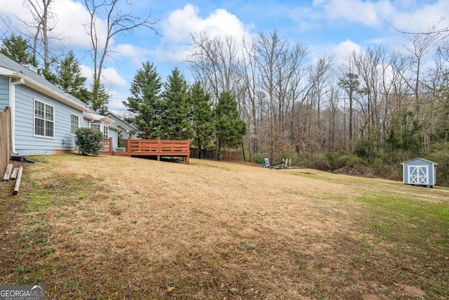 view of yard featuring an outdoor structure, a wooden deck, and a storage shed