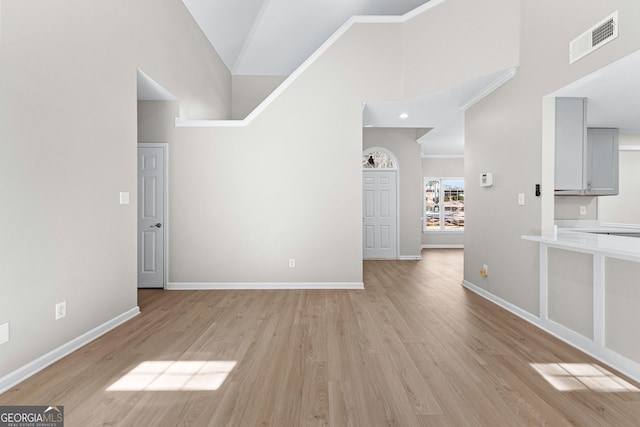 interior space with high vaulted ceiling, baseboards, visible vents, and light wood finished floors