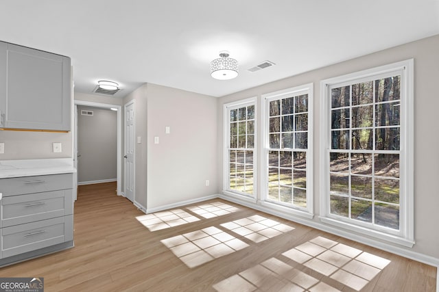 unfurnished dining area with light wood-type flooring, baseboards, and visible vents