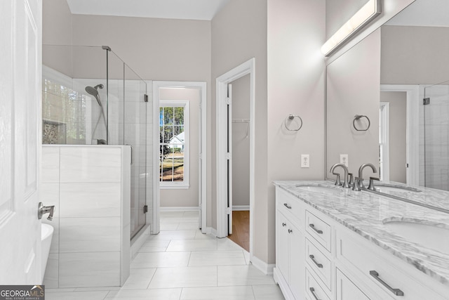 full bathroom featuring a stall shower, a sink, and double vanity