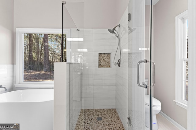 bathroom featuring a soaking tub, a shower stall, and toilet