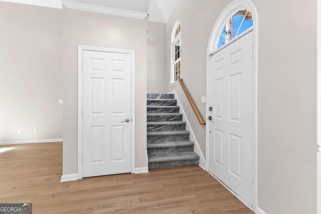 foyer entrance featuring light wood-style floors, stairs, baseboards, and ornamental molding