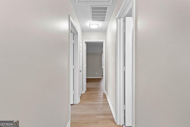 hallway featuring light wood-style flooring, visible vents, and baseboards