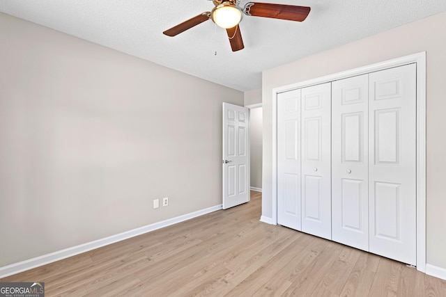 unfurnished bedroom with ceiling fan, a textured ceiling, baseboards, light wood-style floors, and a closet