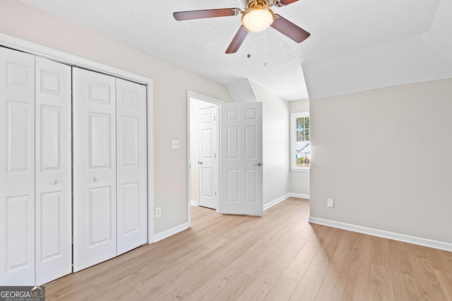 unfurnished bedroom featuring a textured ceiling, a closet, light wood-type flooring, and baseboards