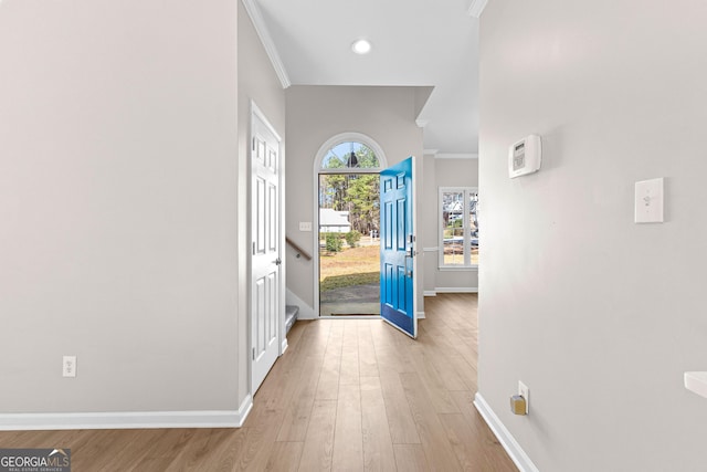 foyer entrance featuring baseboards, light wood-style flooring, and crown molding