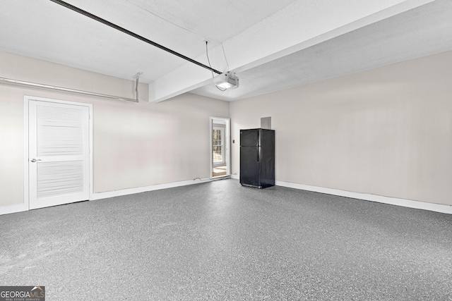 garage with a garage door opener, freestanding refrigerator, and baseboards