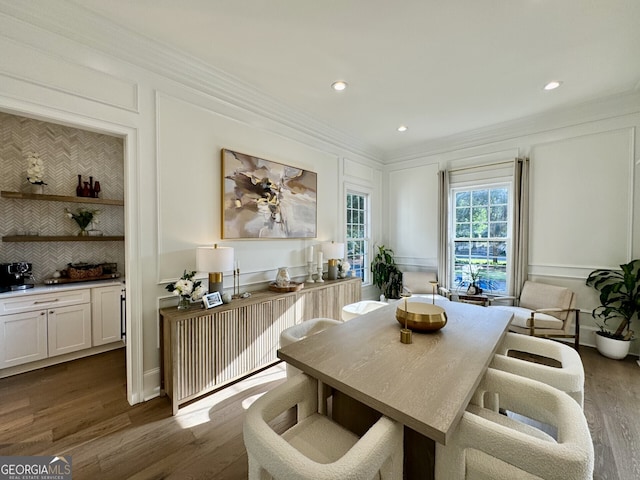 dining area with ornamental molding, recessed lighting, a decorative wall, and wood finished floors