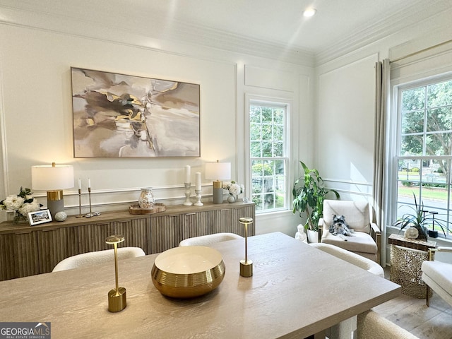 living area with a decorative wall, crown molding, and wood finished floors