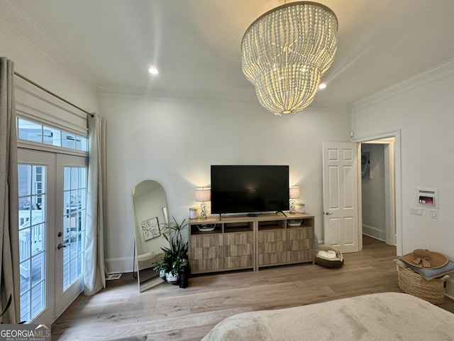 living room featuring french doors, a notable chandelier, crown molding, wood finished floors, and baseboards