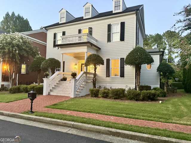 view of front of house with a front yard and a balcony