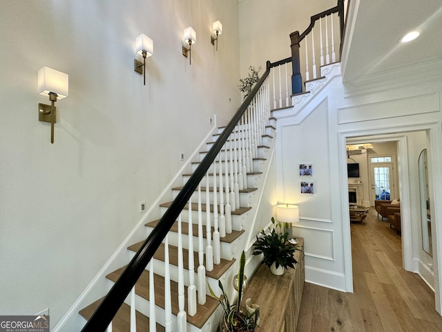 stairs with a decorative wall, baseboards, and wood finished floors