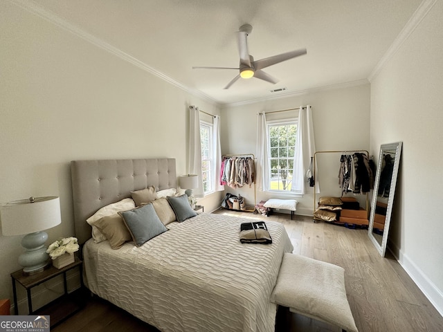 bedroom with baseboards, visible vents, ornamental molding, and wood finished floors