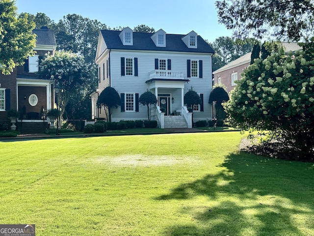 view of front facade with a front yard and a balcony