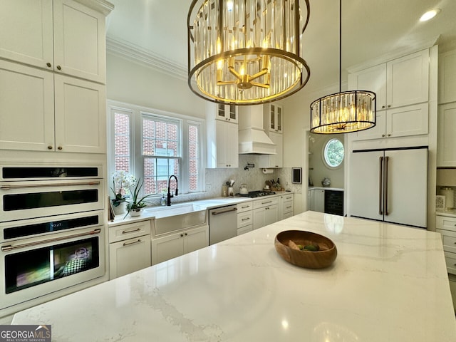 kitchen with white appliances, custom range hood, ornamental molding, a chandelier, and a sink