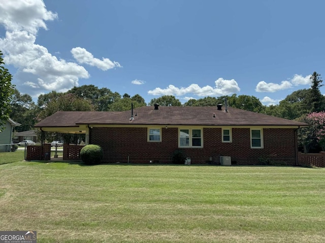 rear view of house with brick siding, fence, and a yard