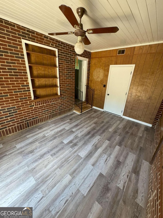 interior space featuring wood ceiling, brick wall, visible vents, and wood finished floors