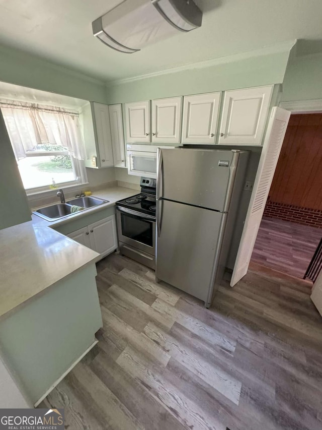 kitchen with white cabinets, light wood-style flooring, stainless steel appliances, light countertops, and a sink