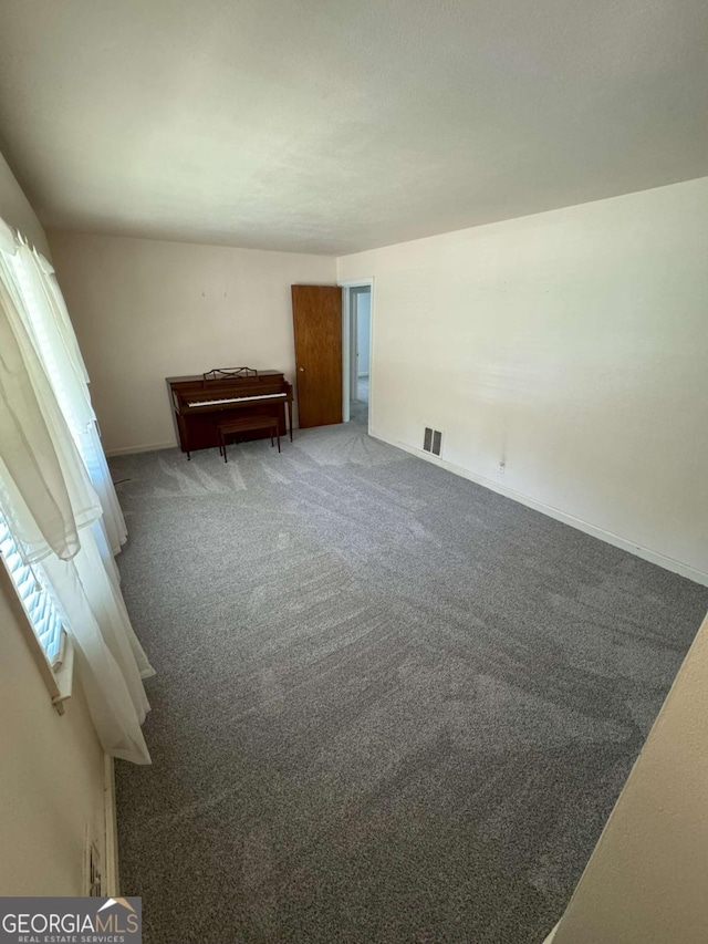 unfurnished bedroom with multiple windows, carpet, visible vents, and baseboards